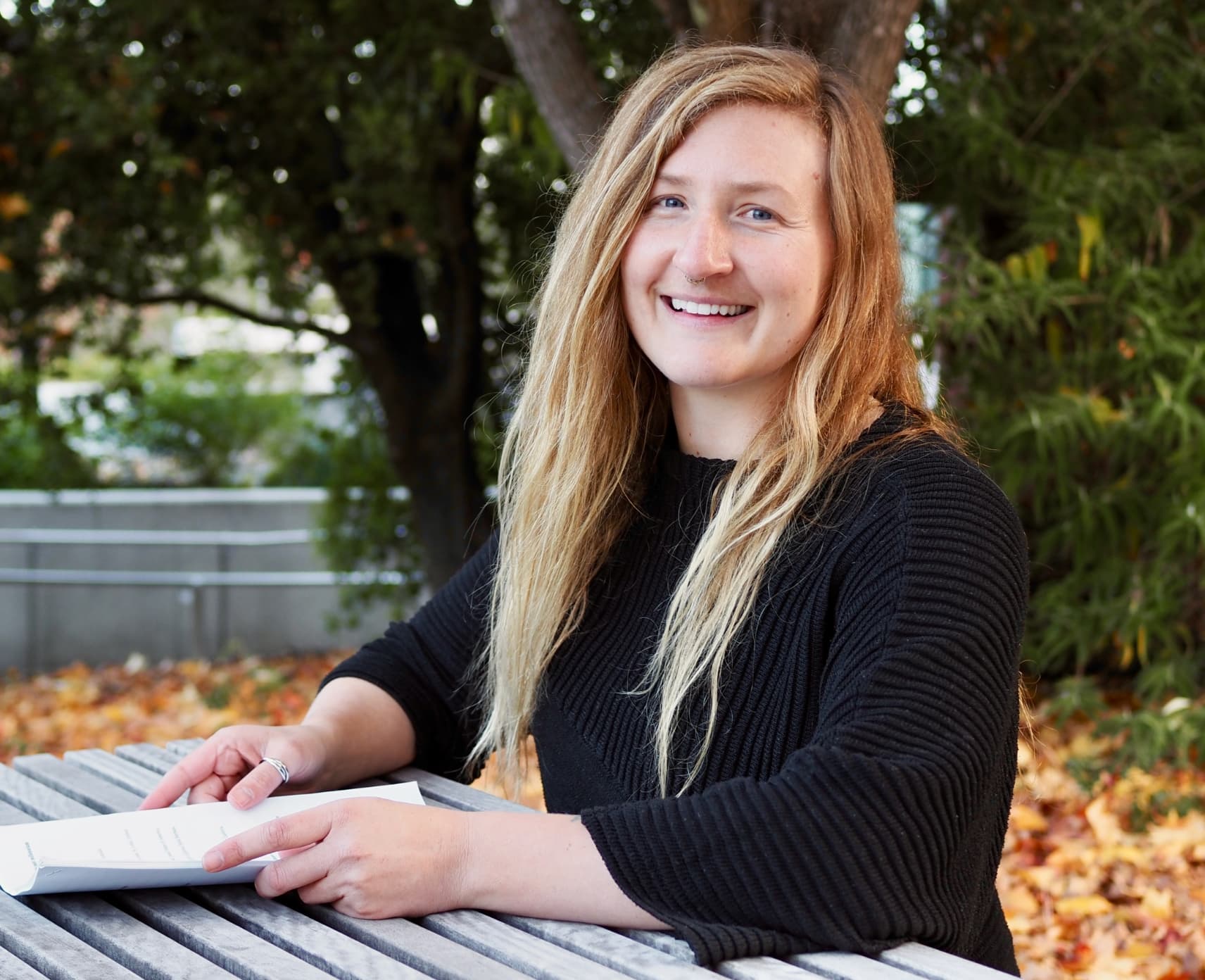 Georgy Falster is sitting on a bench holding sheets of paper