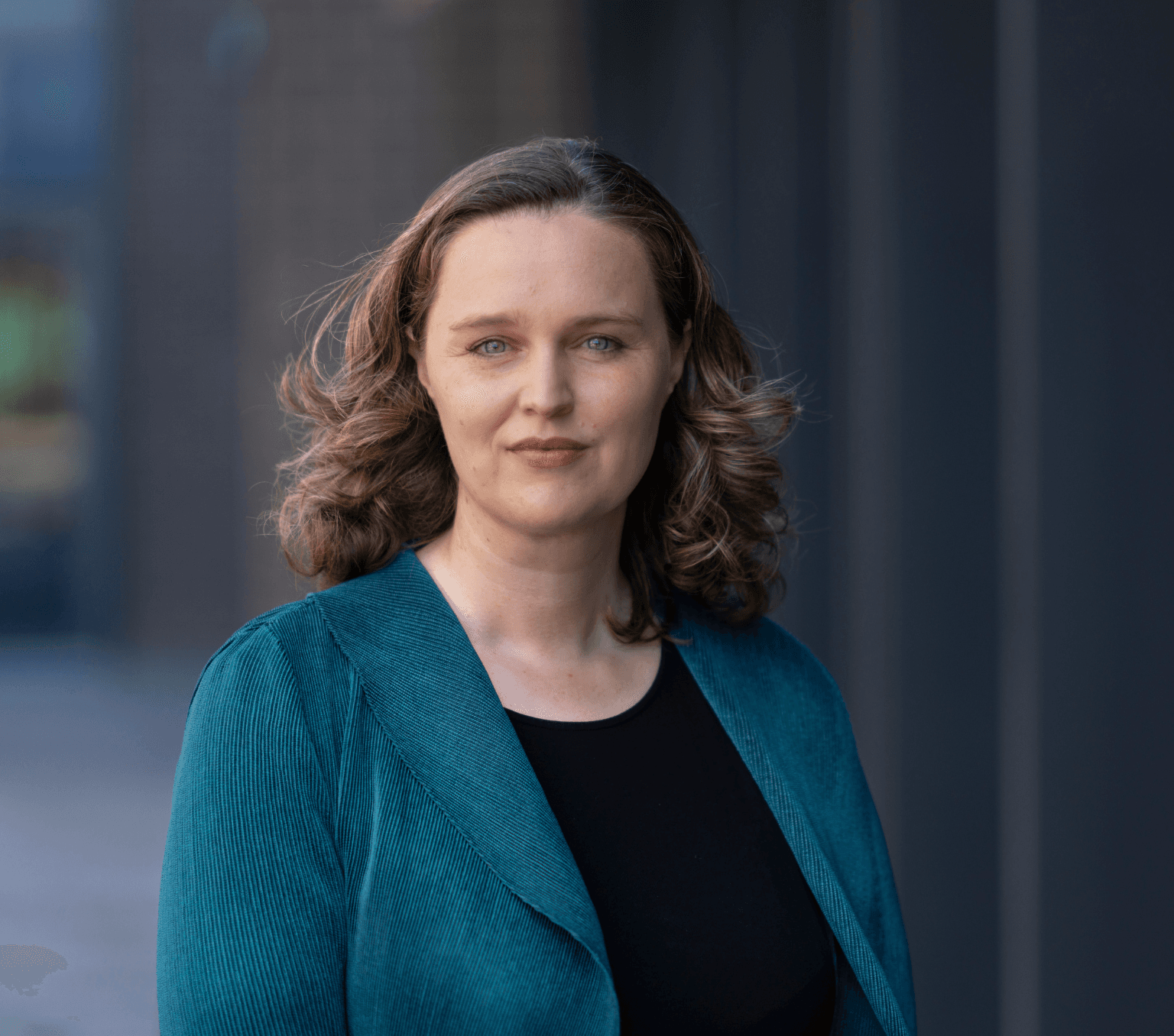 Anthea Roberts, a woman with shoulder-length curly hair, wears a green jacket and a black top.