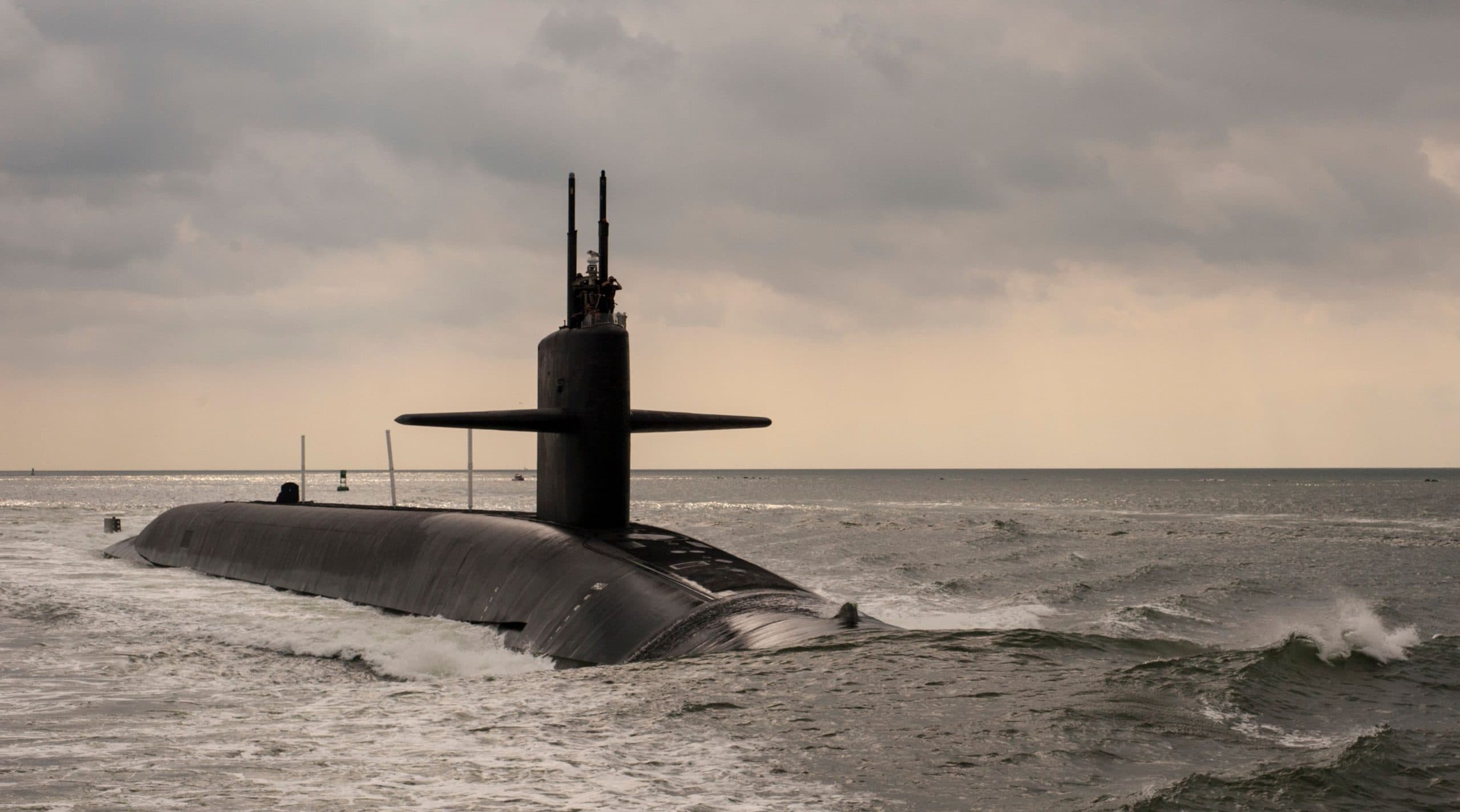 The top of a submarine glides through the water.