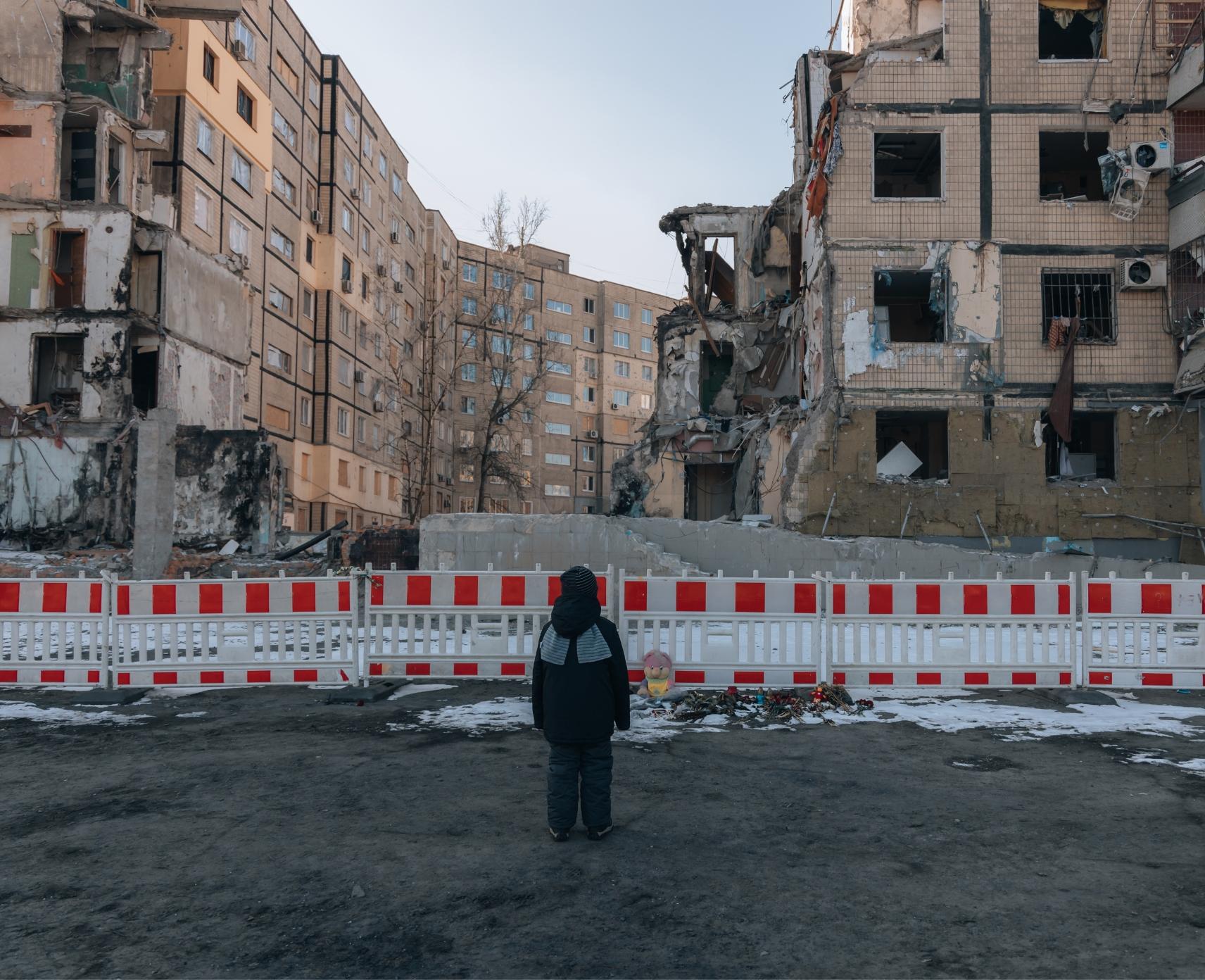 A child observes a residential building destroyed by an explosion after a Russian missile attack.