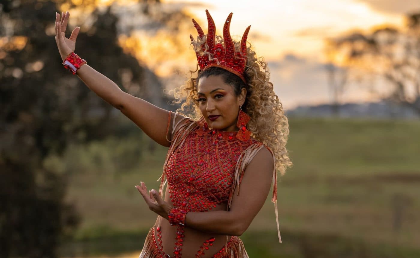 A combination of drag queens, ballet dancers and Brazilian funk dancers wearing colourful costumers filled to the brim with sequins. They are all dancing in a field in regional Victoria.