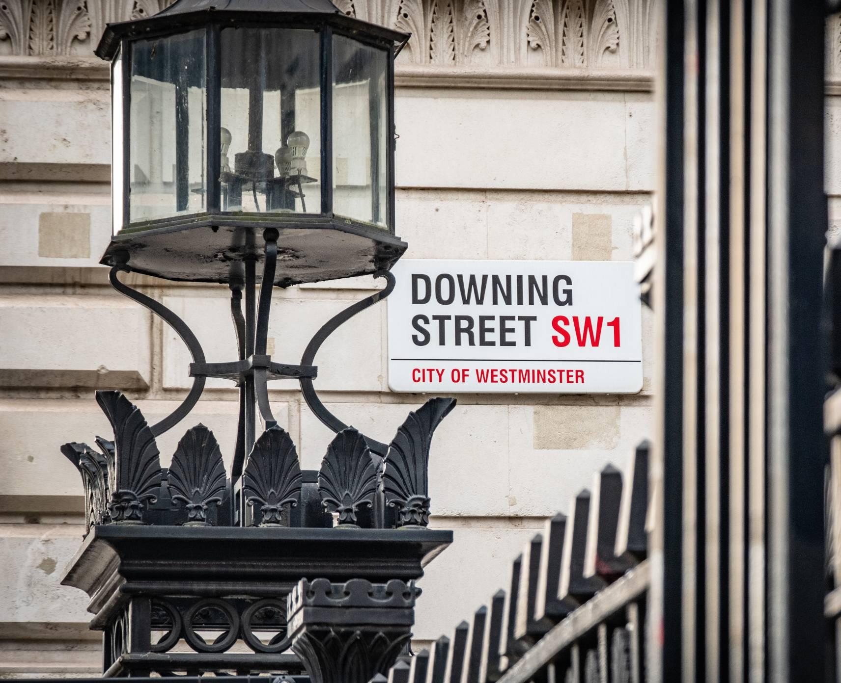 A street sign in England that reads "Downing Street SW1"