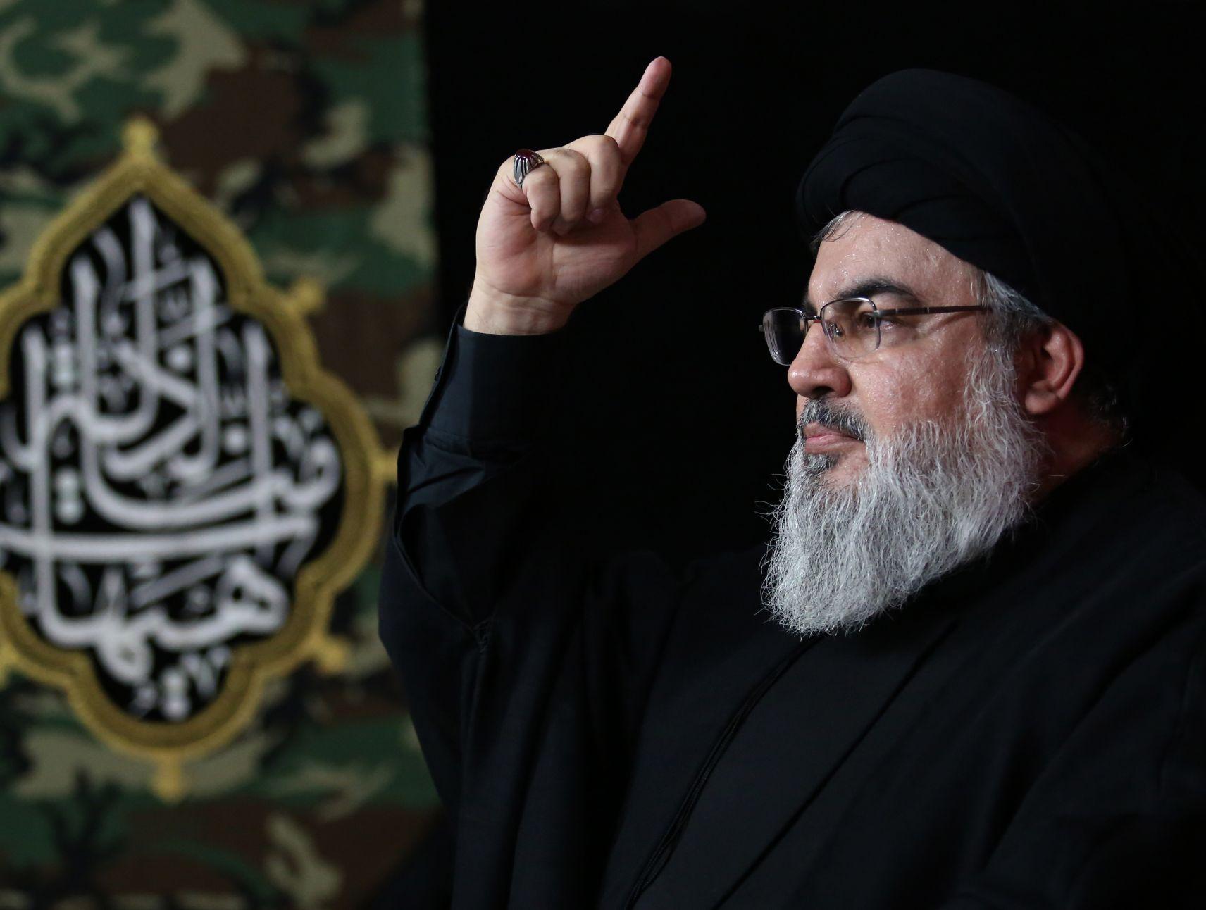 Hassan Nasrallah in profile, points a finger to the sky