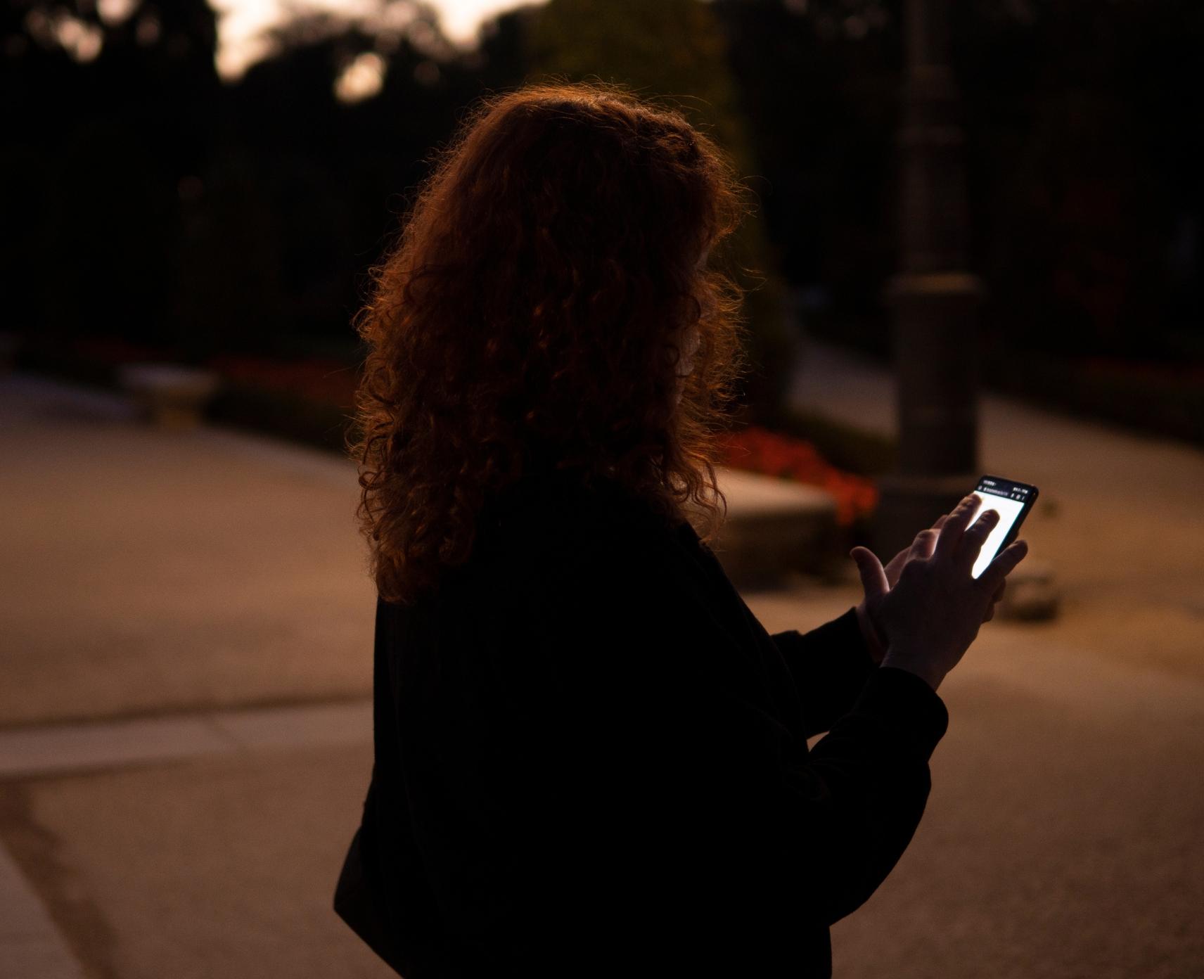 Woman with red hair using phone at night. Telemarketer