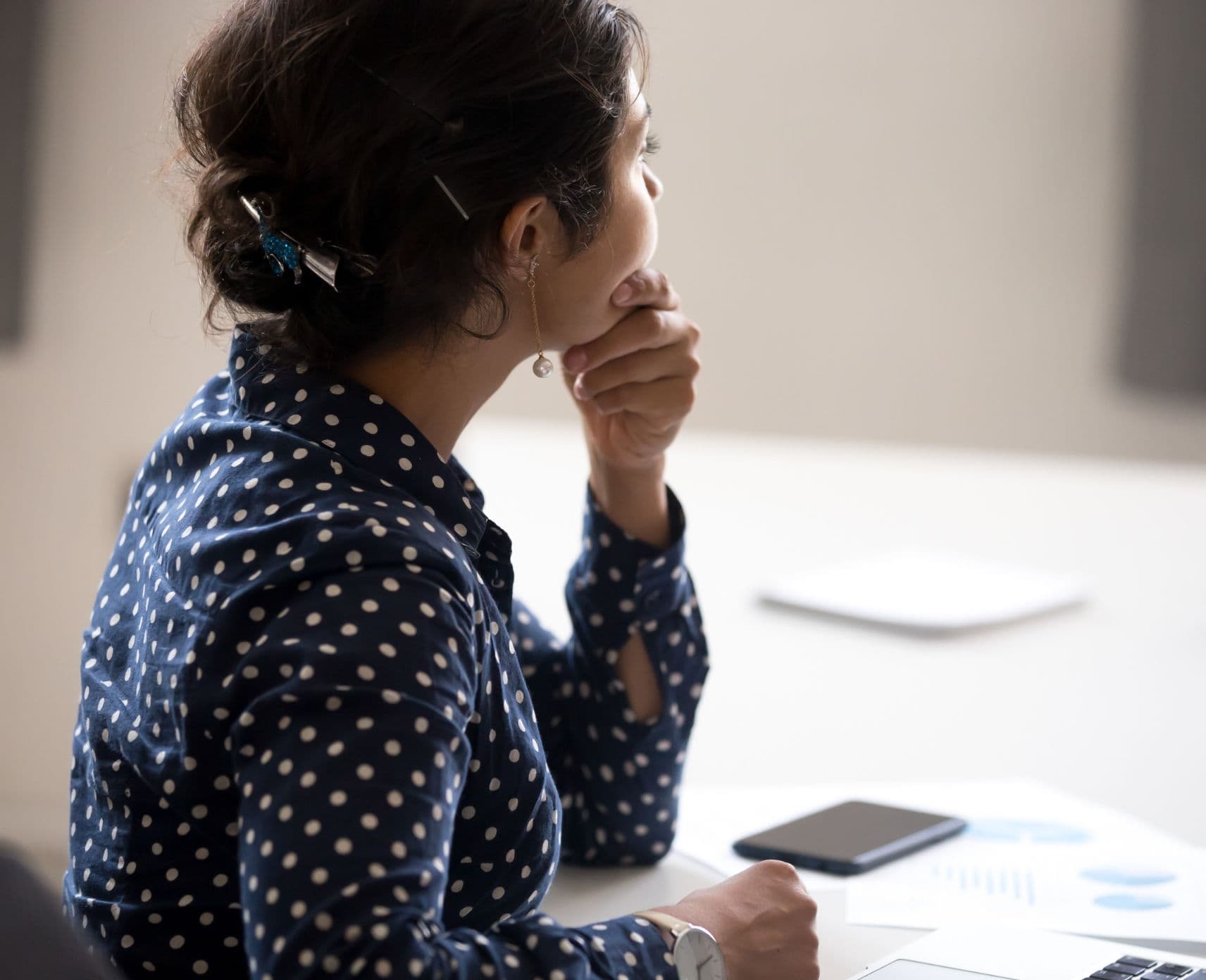 A woman sitting at an office, looking away from the camera