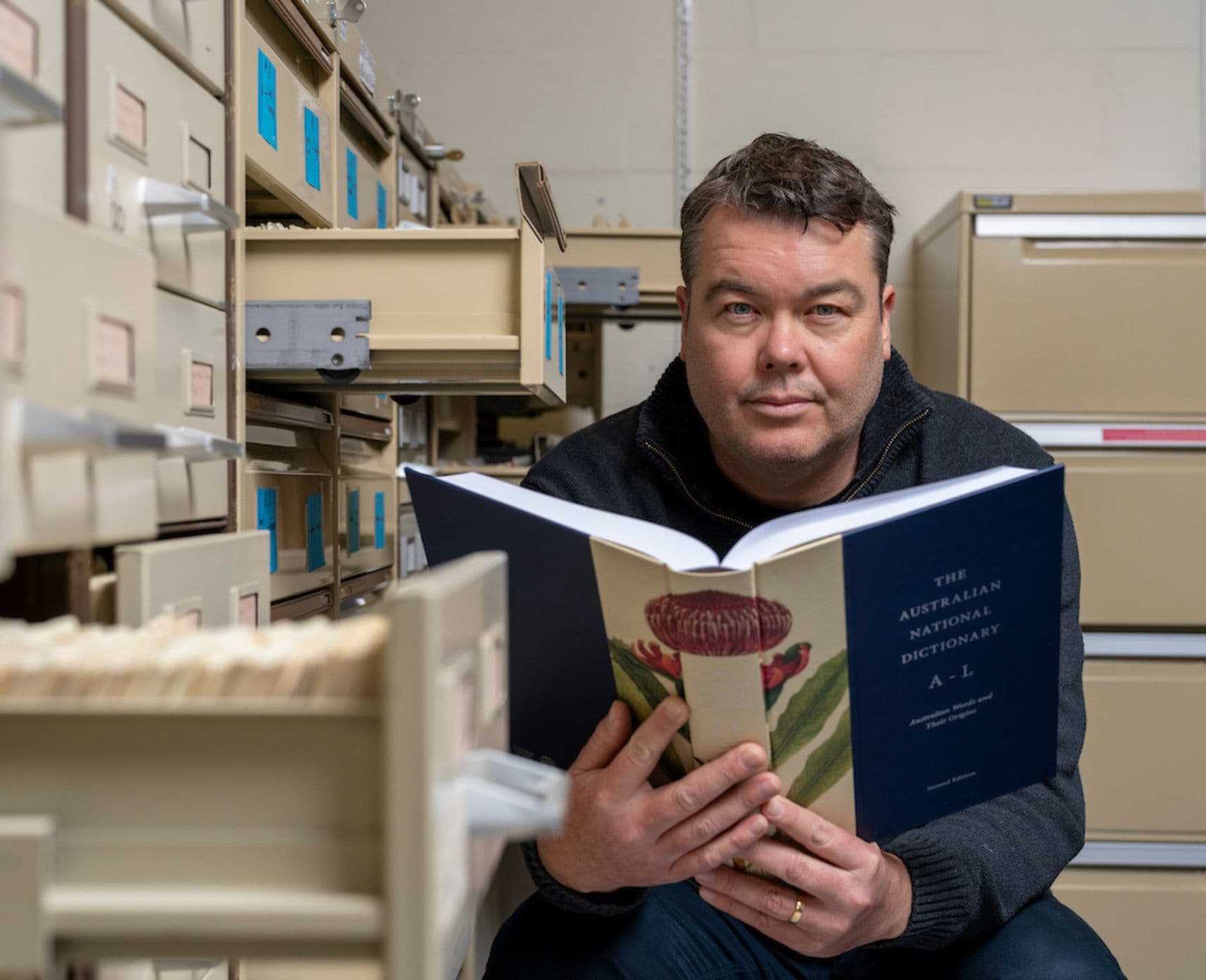 Mark Gwynn poses with a dictionary at The Australian National Dictionary Centre