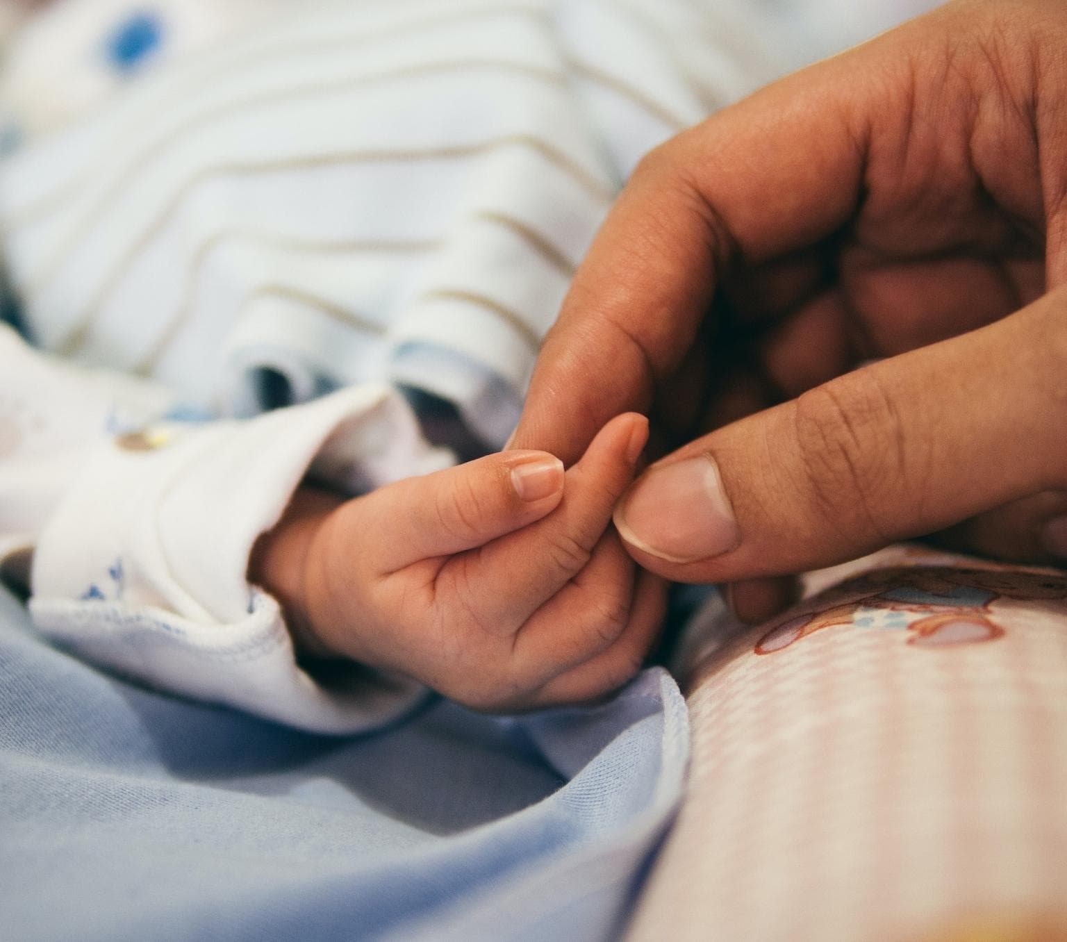 woman's hand is holding a babies hand
