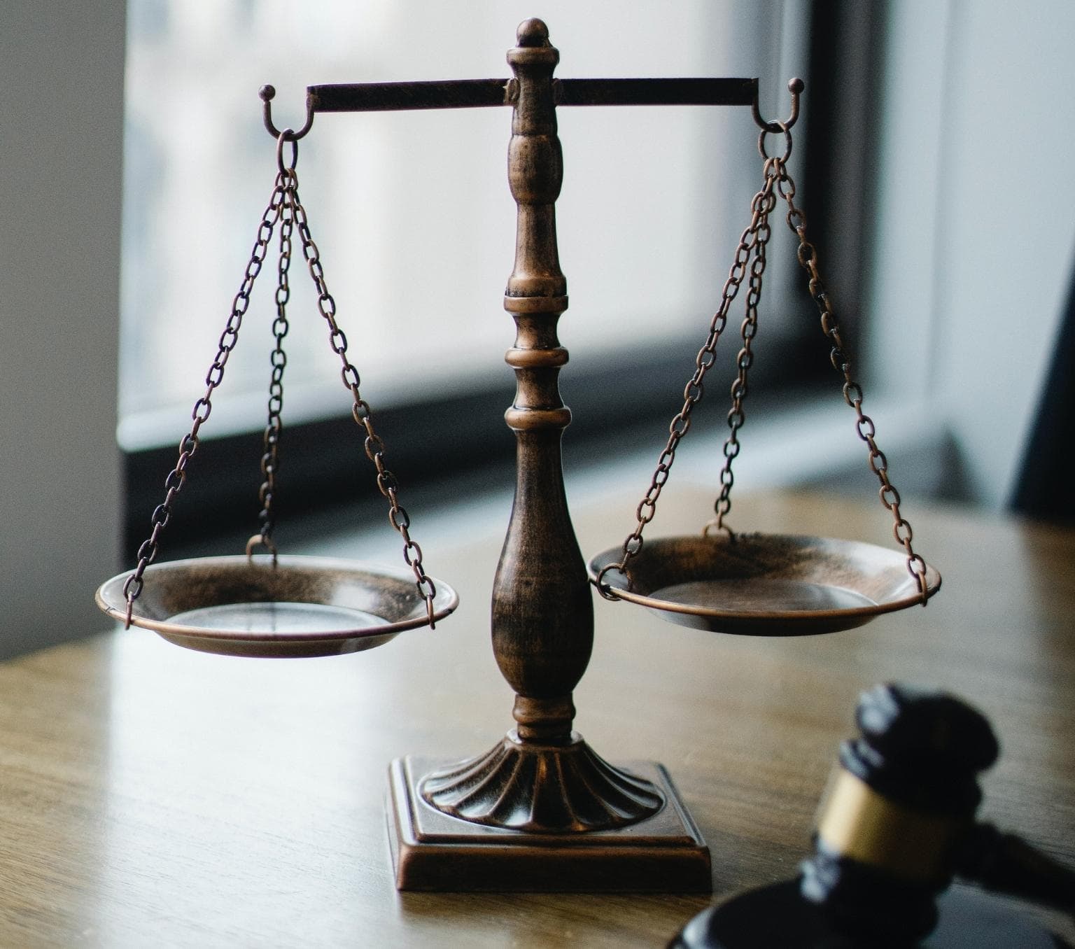 bronze scales with two weights places on a wooden table. a wooden hammer is pictured in the corner of the foreground