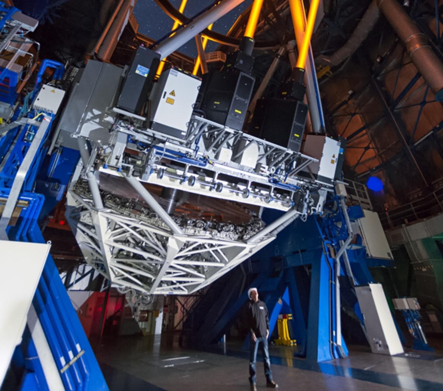man is standing looking up at a massive space instrumentation device