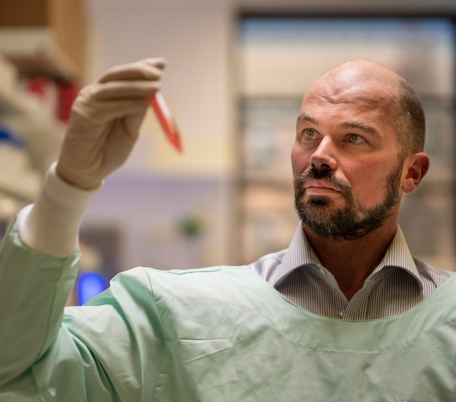 Professor David Nisbet inspecting the hydrogel. The substance is orange and is in a test tube.