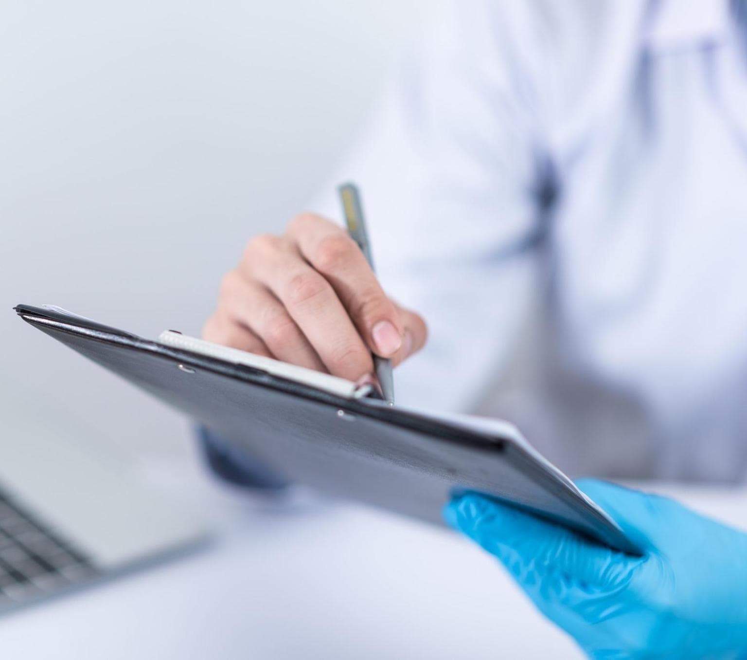 An unidentified doctor writing on a clipboard.