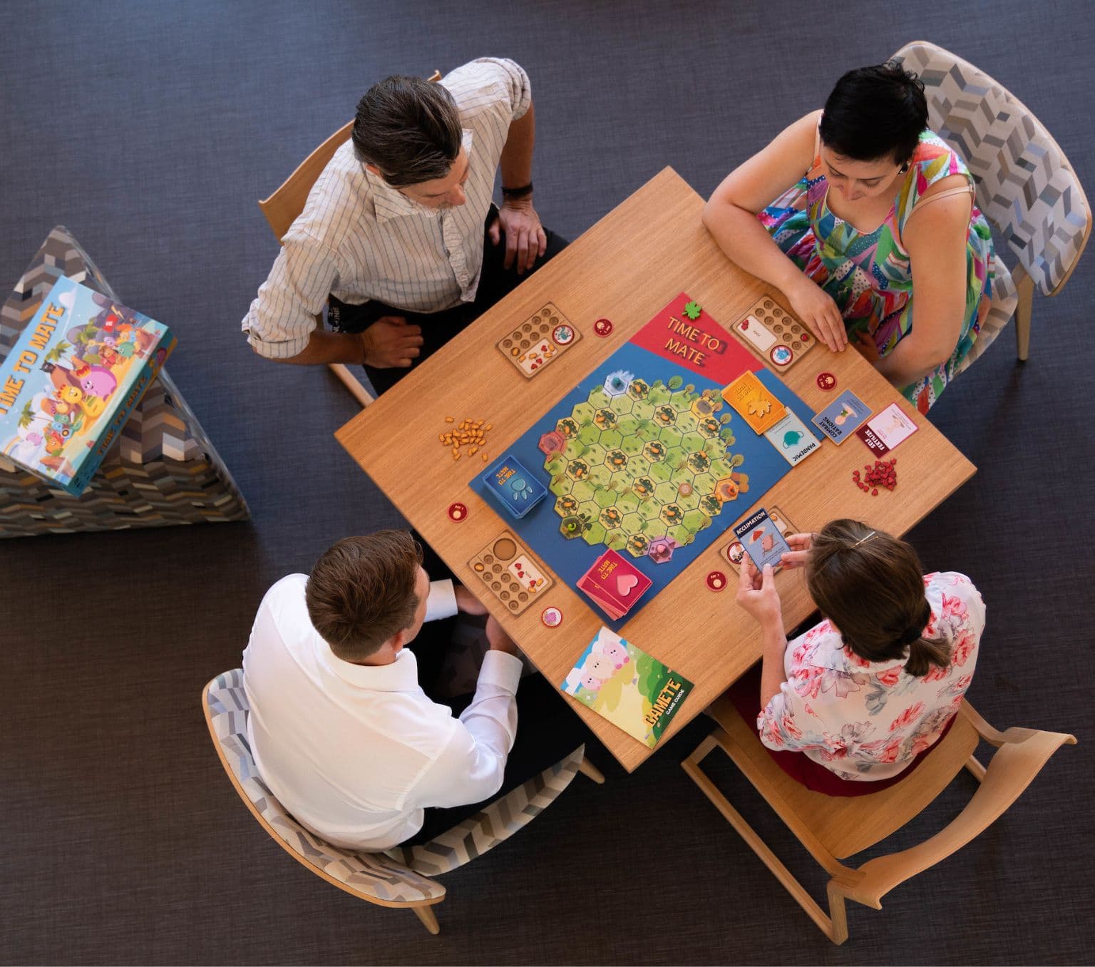 4 people sit around a table playing a board game.
