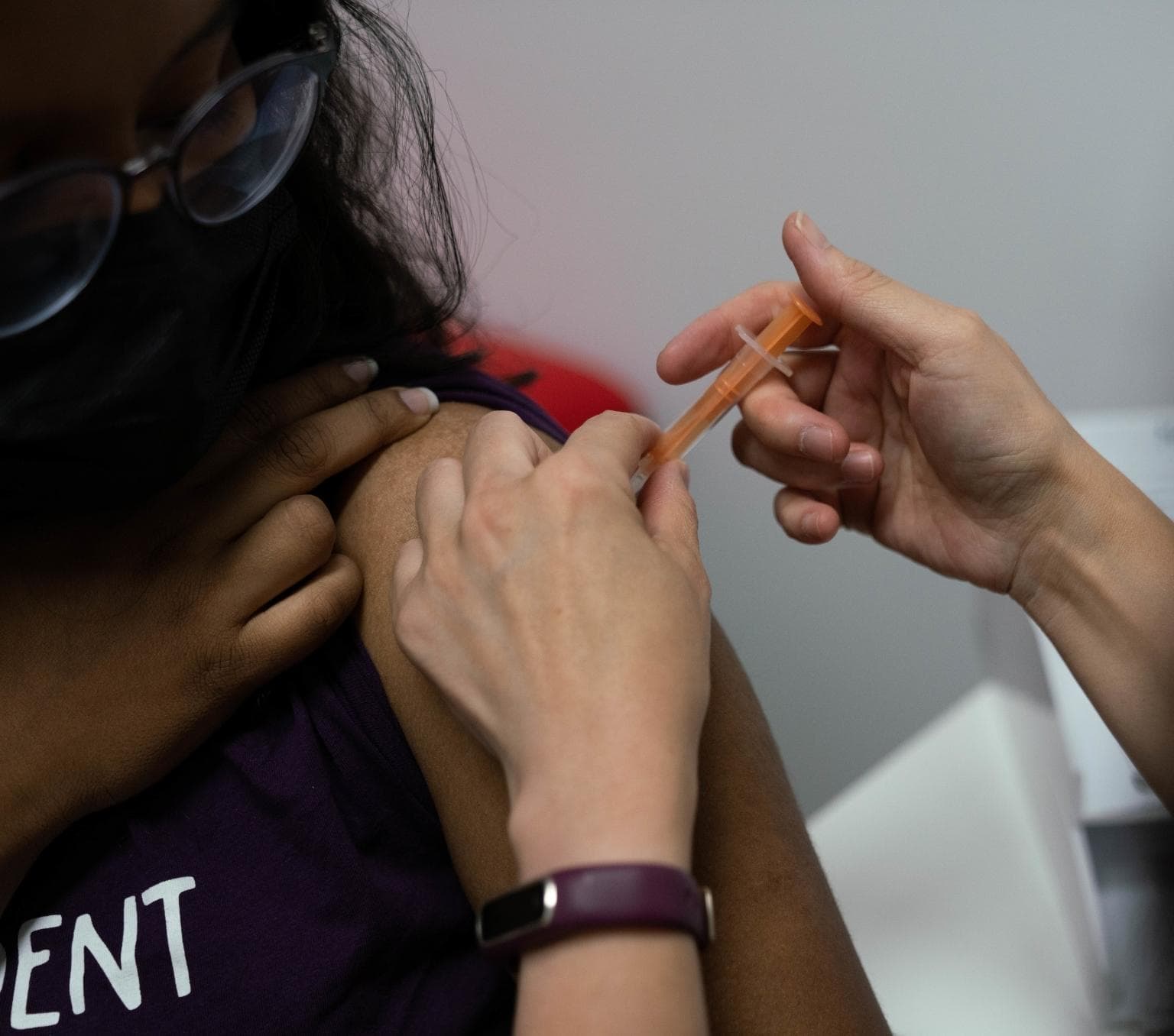 close-up of a women wearing a mask and receiving a vaccine.