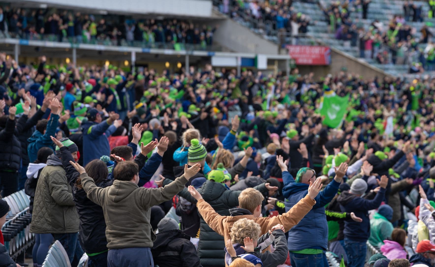 Crowd of supporters at NRL game clap in unison