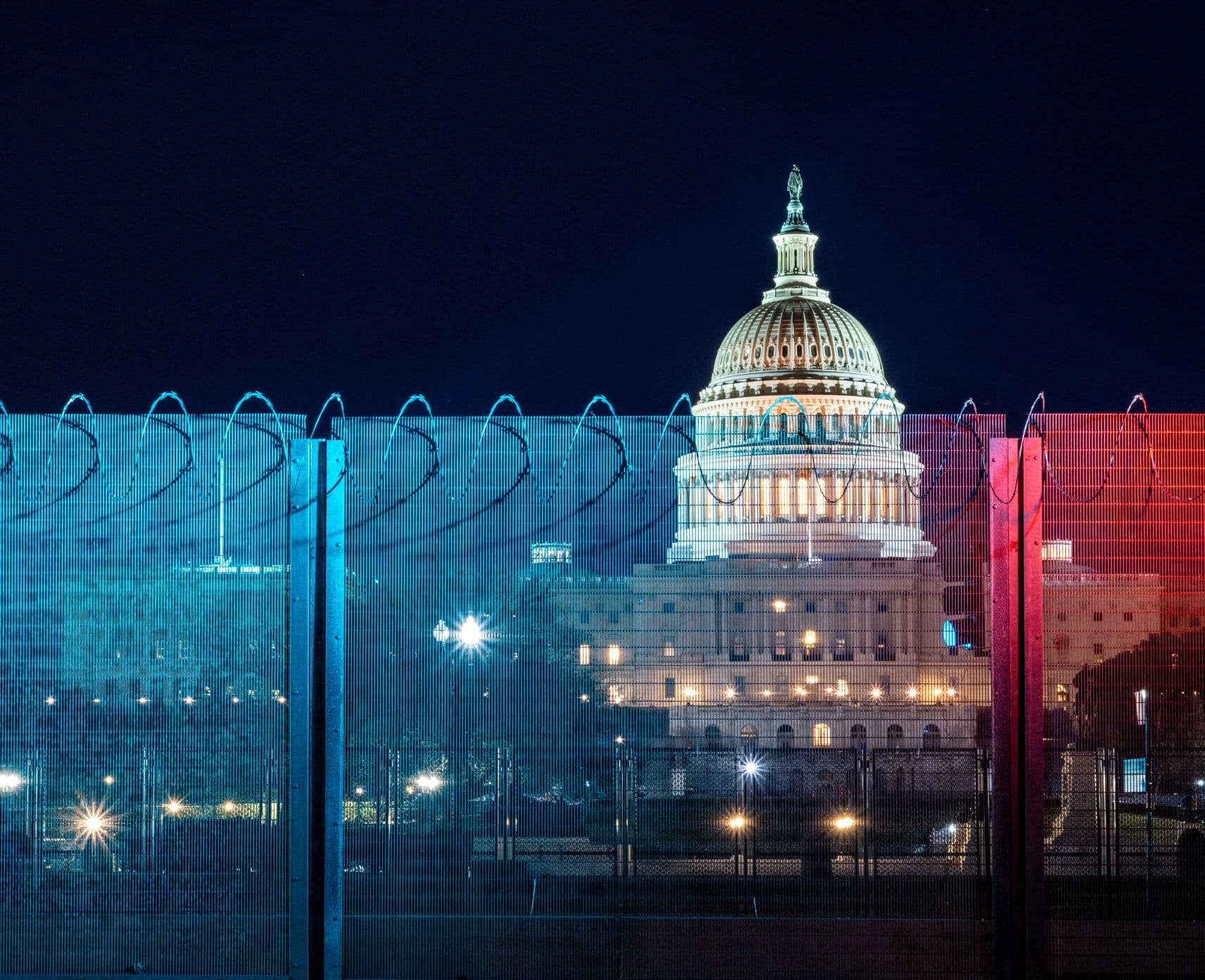 Security fence with blue and red light in front of the United States Capitol