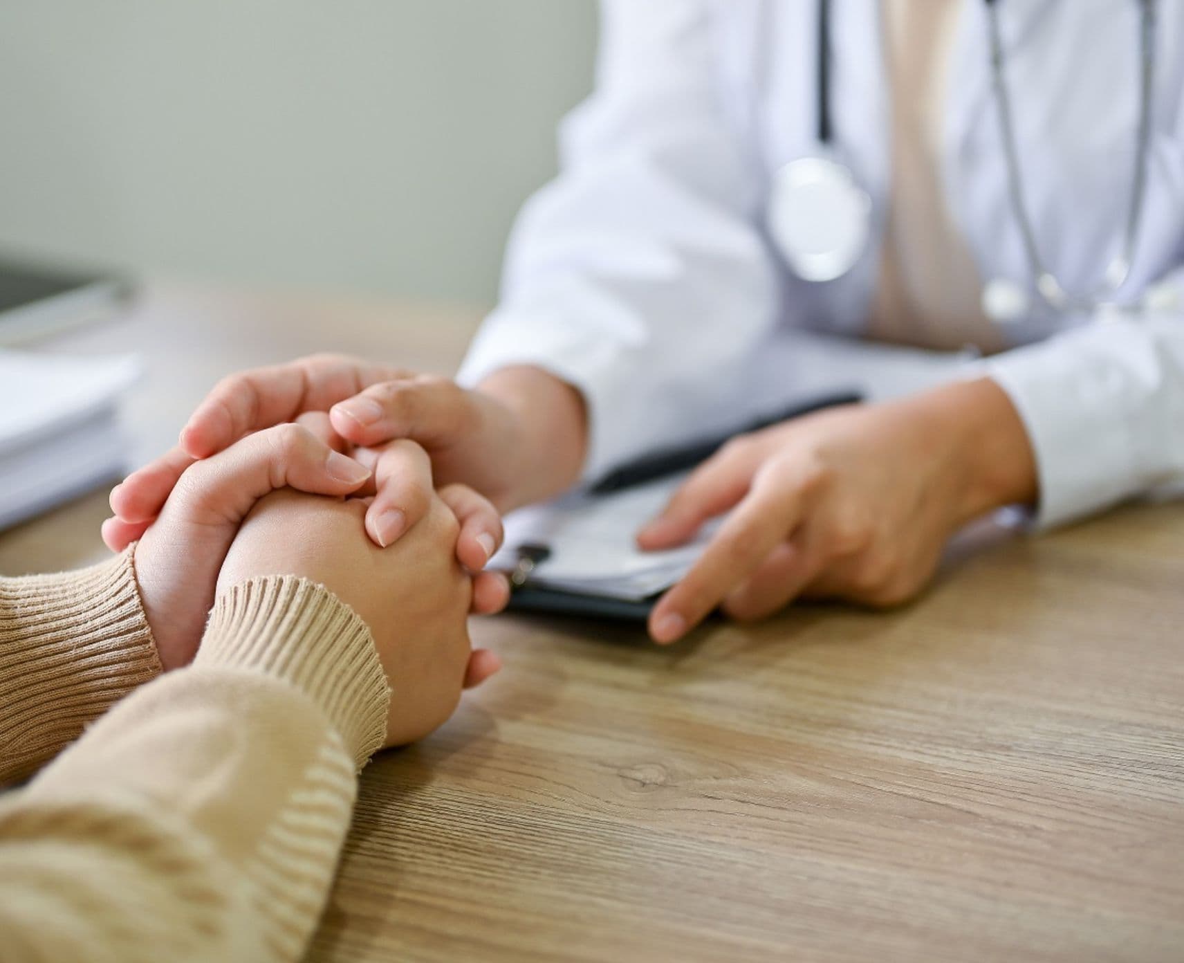 Adoctor places his hand over the hands of a patient.