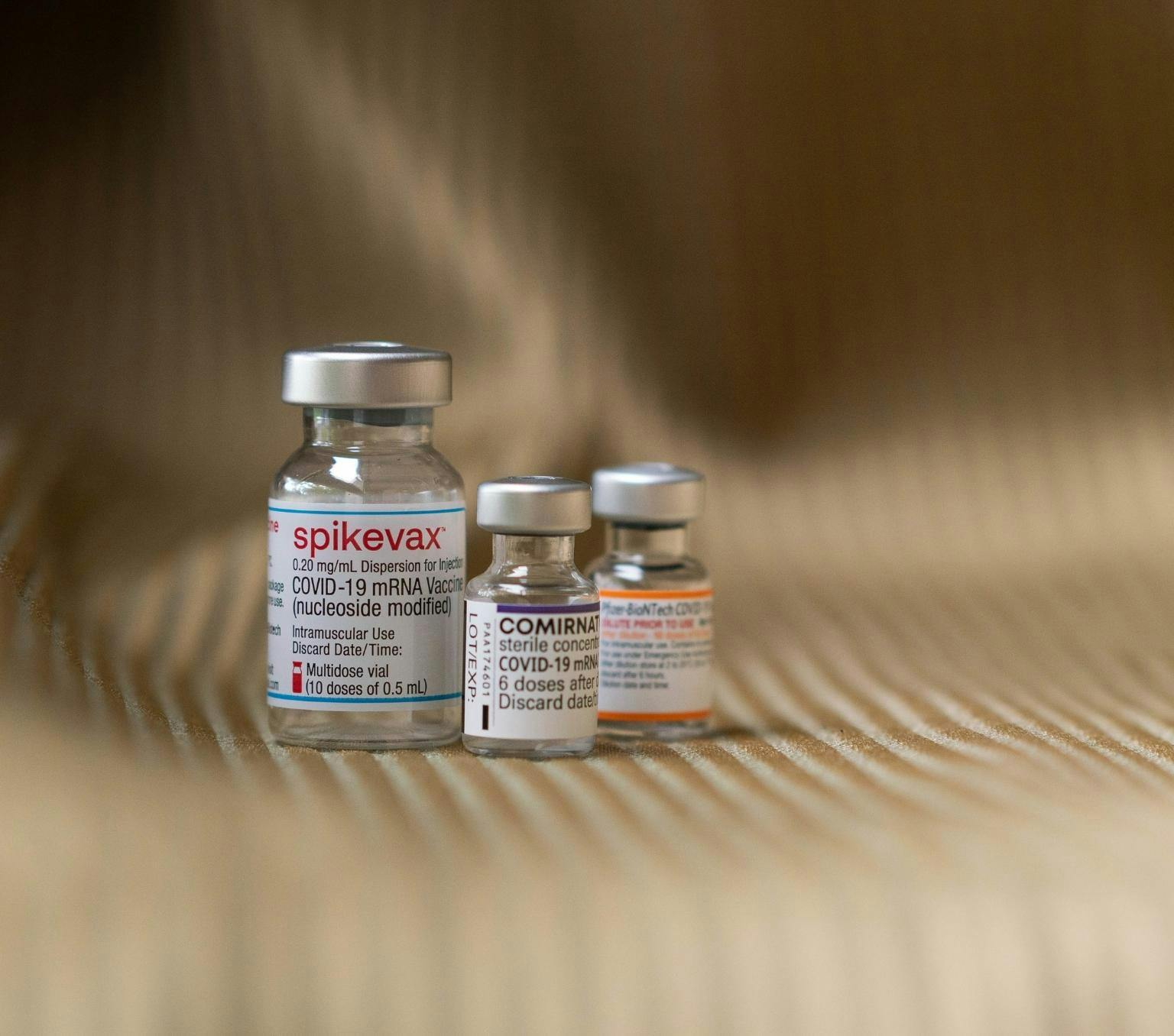 Three vials side by side containing the COVID-19 vaccine.