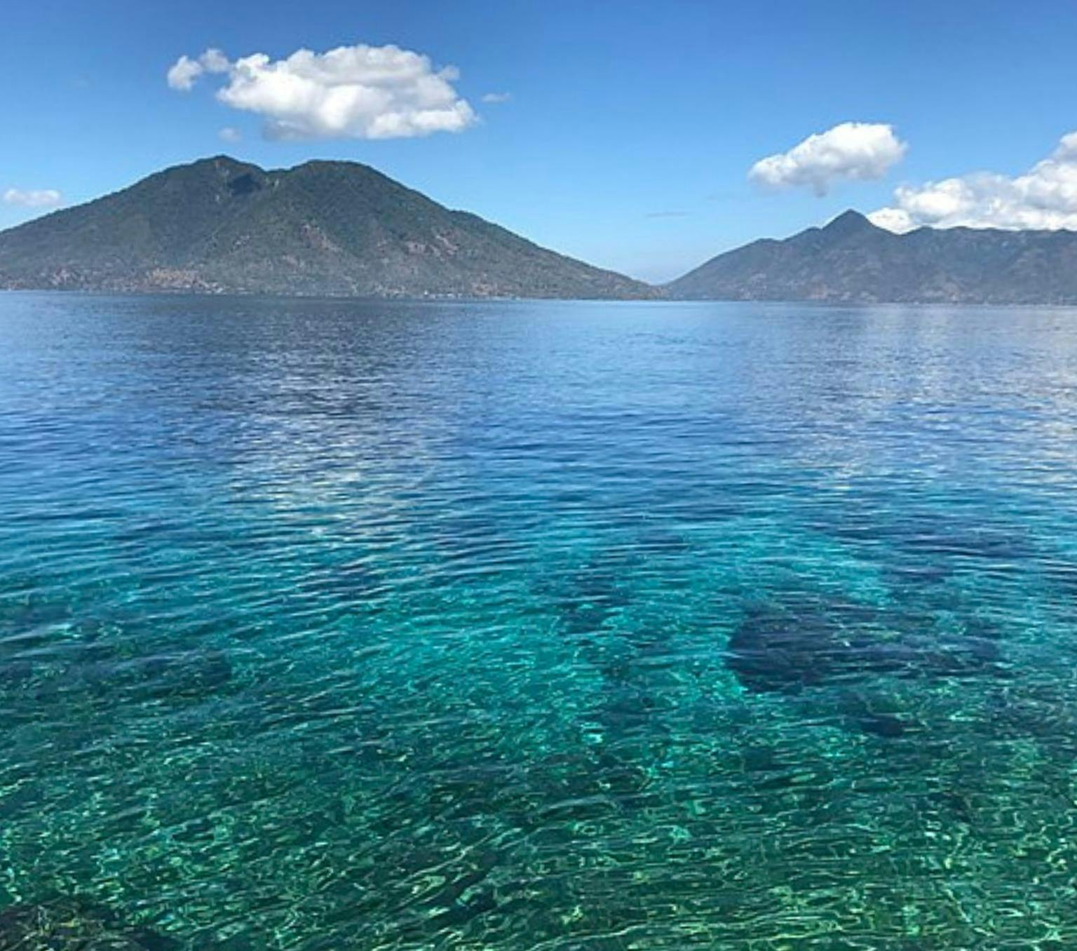 Clear blue-green water and in the distance is a bare mountain.