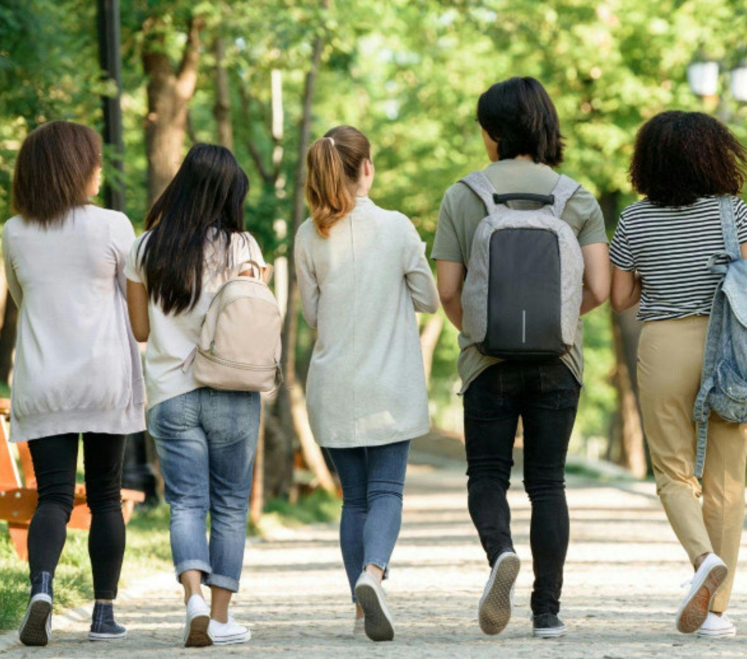 5 students walking in an outdoor area.