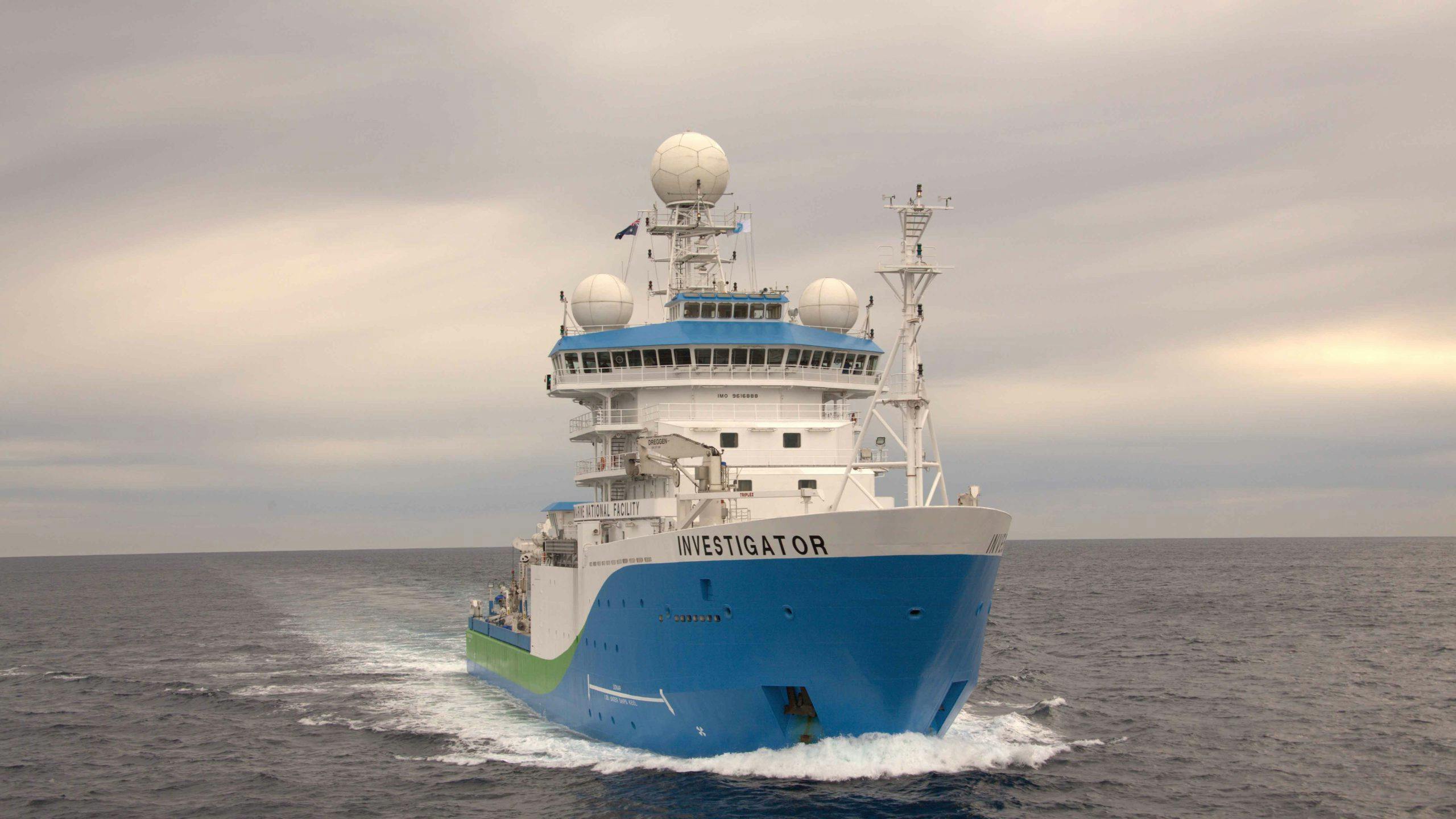 large boat with a blue painted hull is pictured in the ocean.