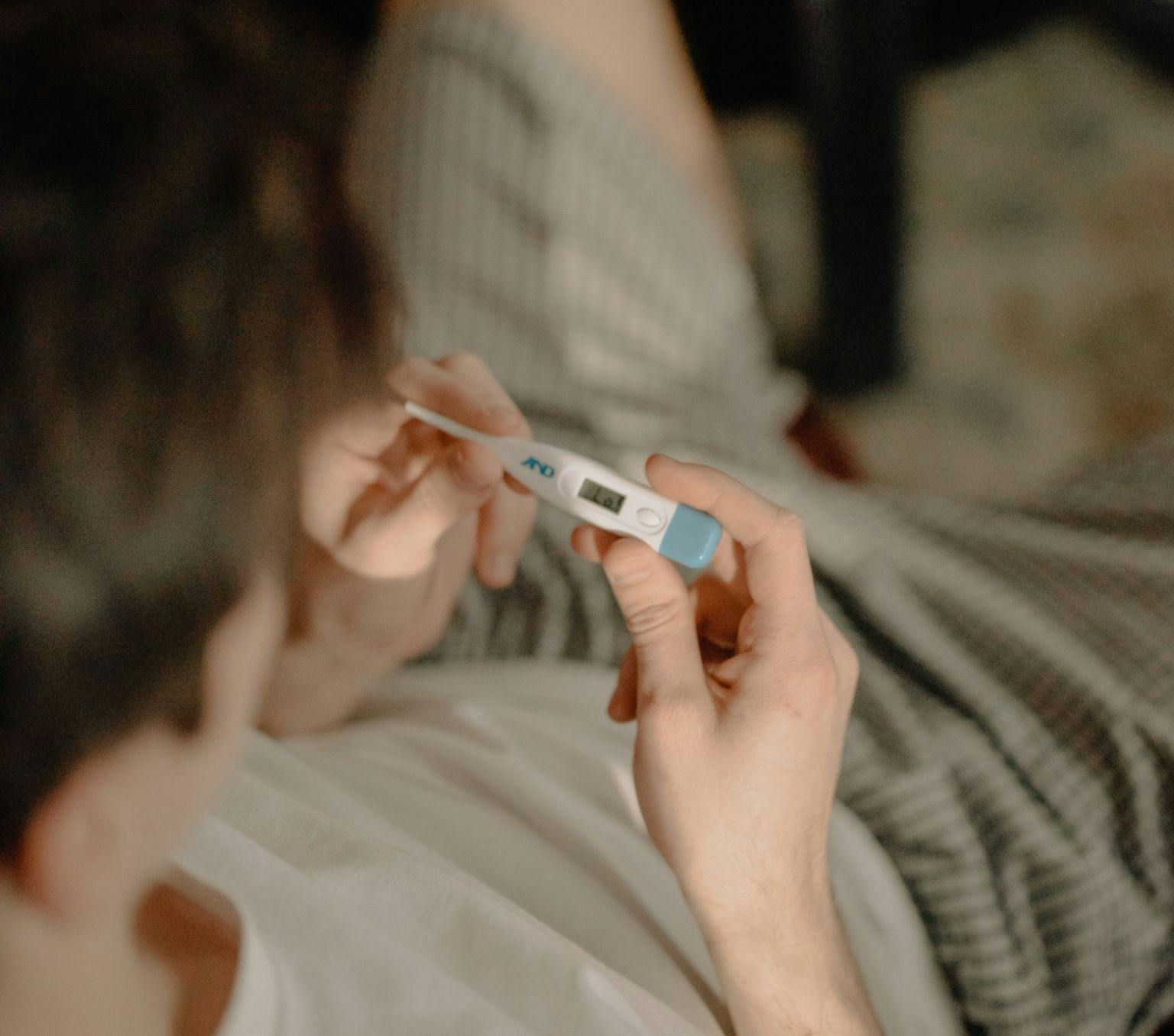 person holding thermometer looking down