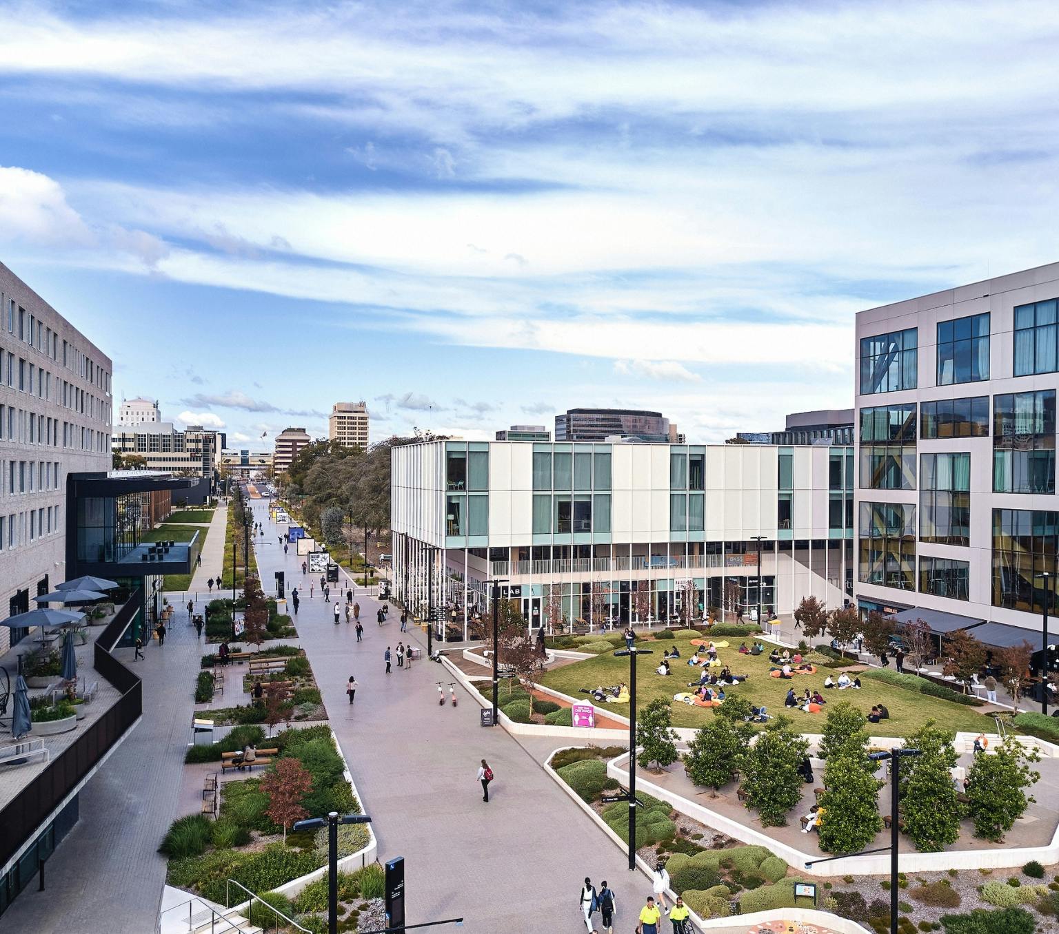 Aerial view of a walkway with buildings and grass on either side and people walking