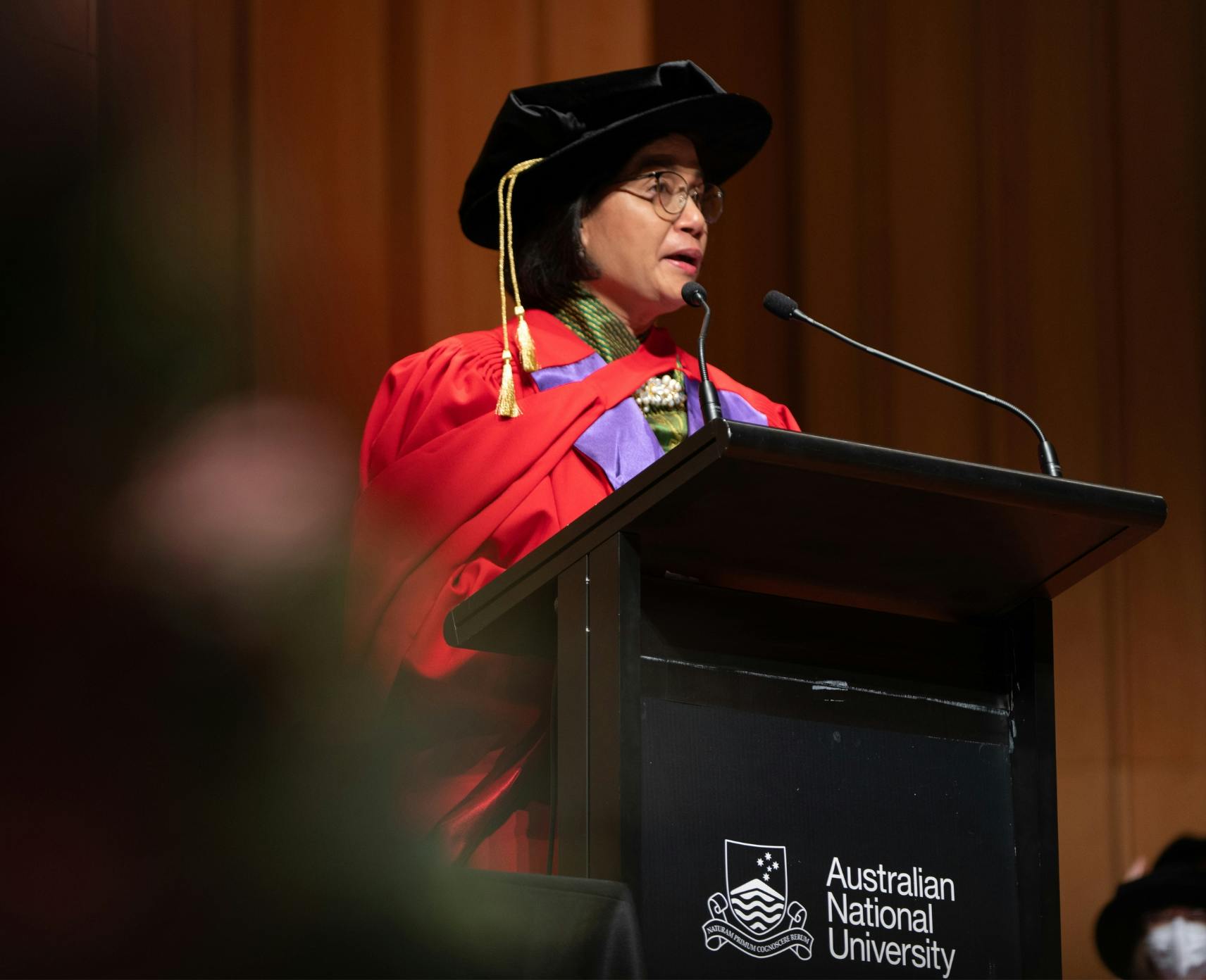 Sri Mulyani Indrawati dressed in academic regalia delivers a speech at Llewellyn Hall, ANU