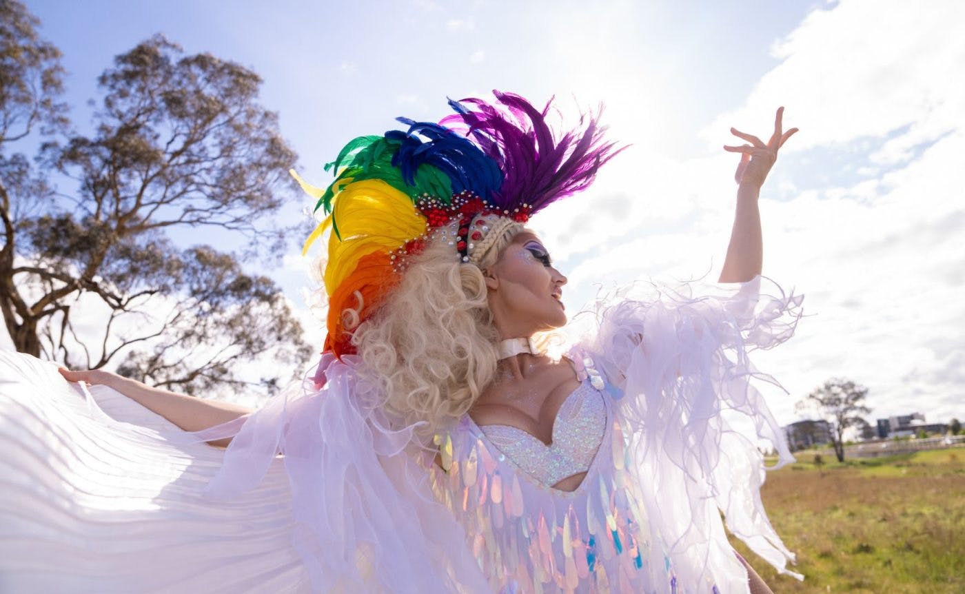 A combination of drag queens, ballet dancers and Brazilian funk dancers wearing colourful costumers filled to the brim with sequins. They are all dancing in a field in regional Victoria.