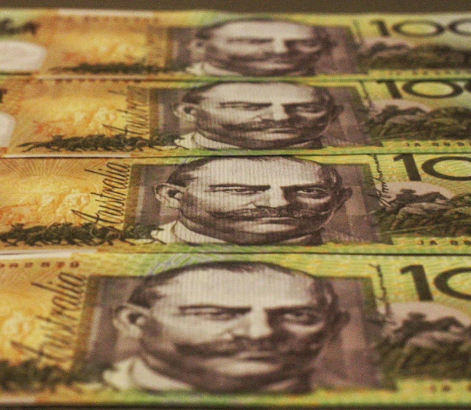 line of Australian hundred dollar bills are pictured. The bills are green and yellow and feature a black and white drawing of the face of a man